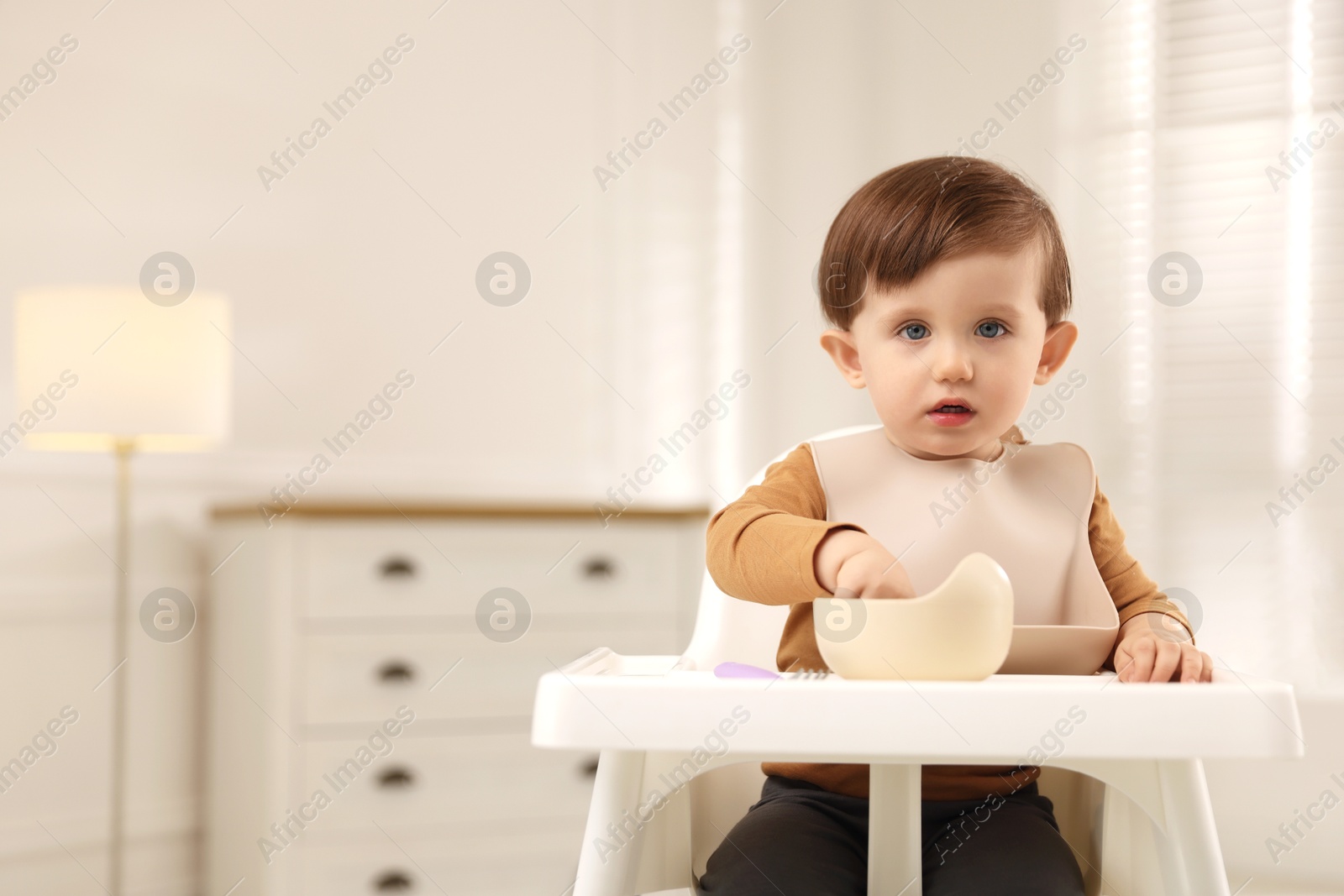 Photo of Cute little baby eating healthy food from bowl in high chair at home, space for text