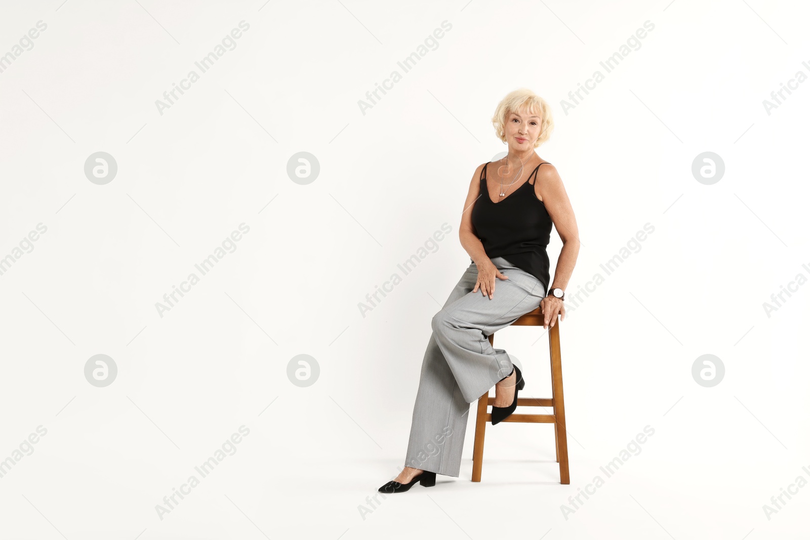 Photo of Beautiful senior woman sitting on chair against white background, space for text