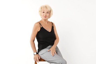 Photo of Beautiful senior woman sitting on chair against white background