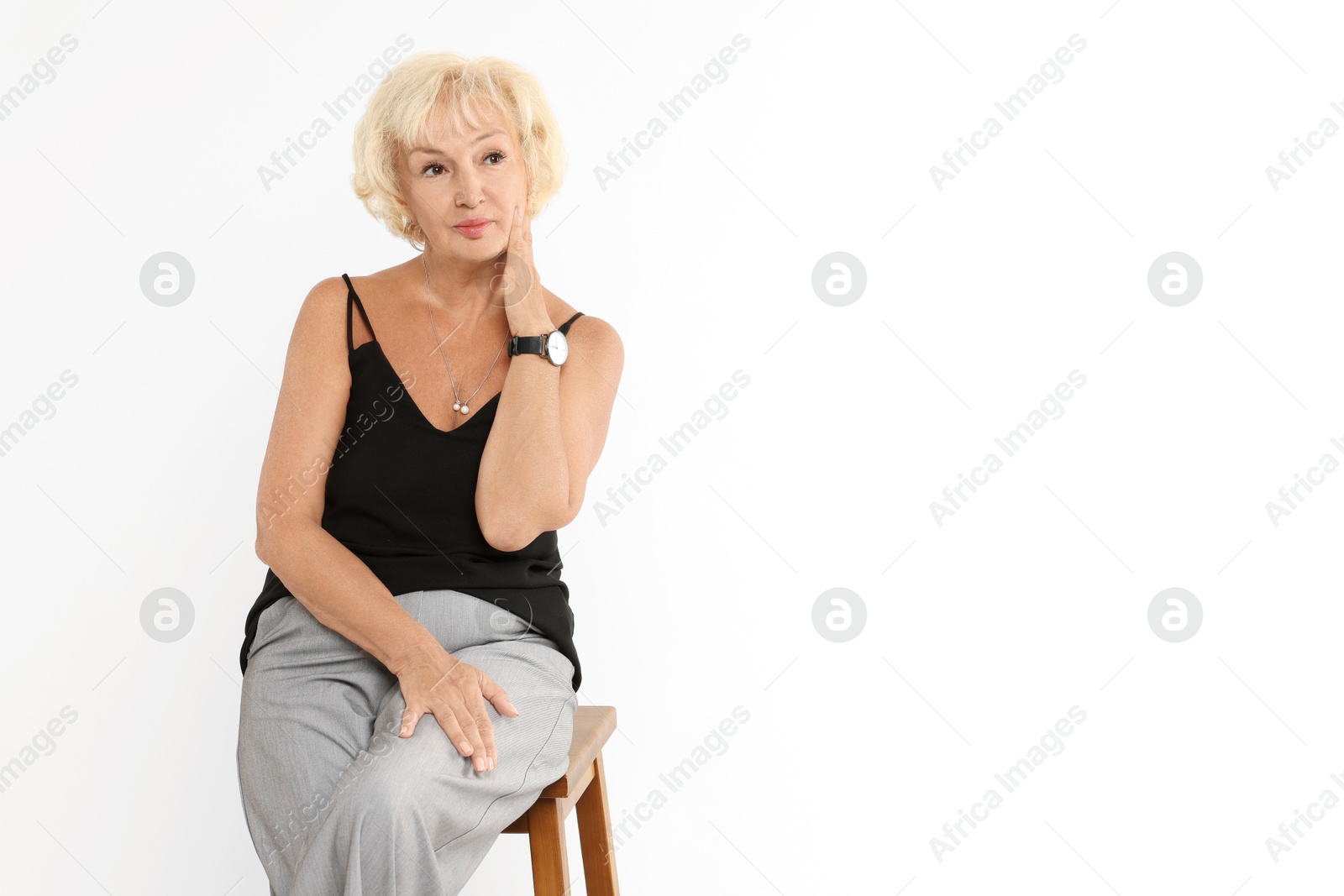 Photo of Beautiful senior woman sitting on chair against white background, space for text