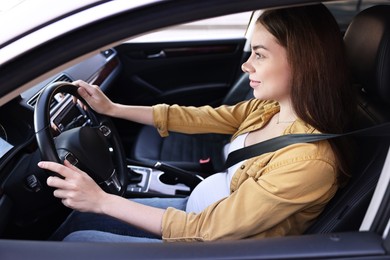 Photo of Pregnant woman with safety belt driving car