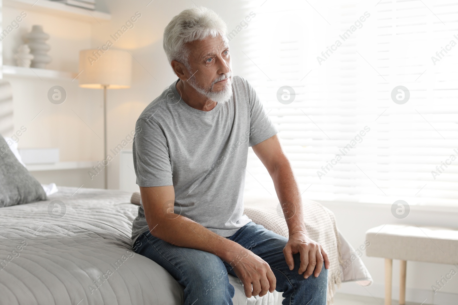 Photo of Lonely senior man sitting on bed at home