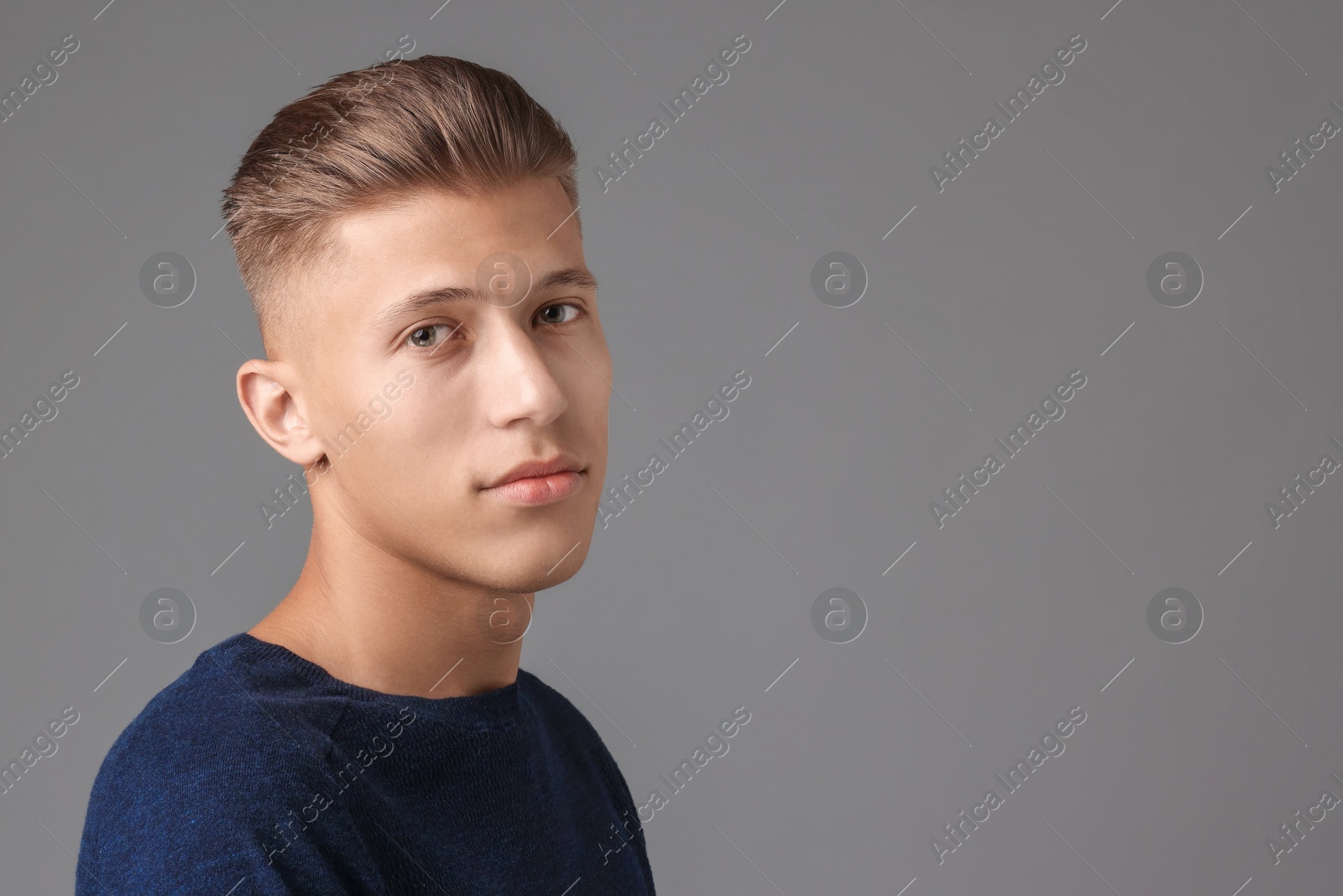 Photo of Handsome young man with stylish haircut on grey background. Space for text