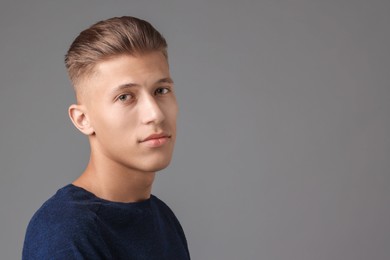 Photo of Handsome young man with stylish haircut on grey background. Space for text