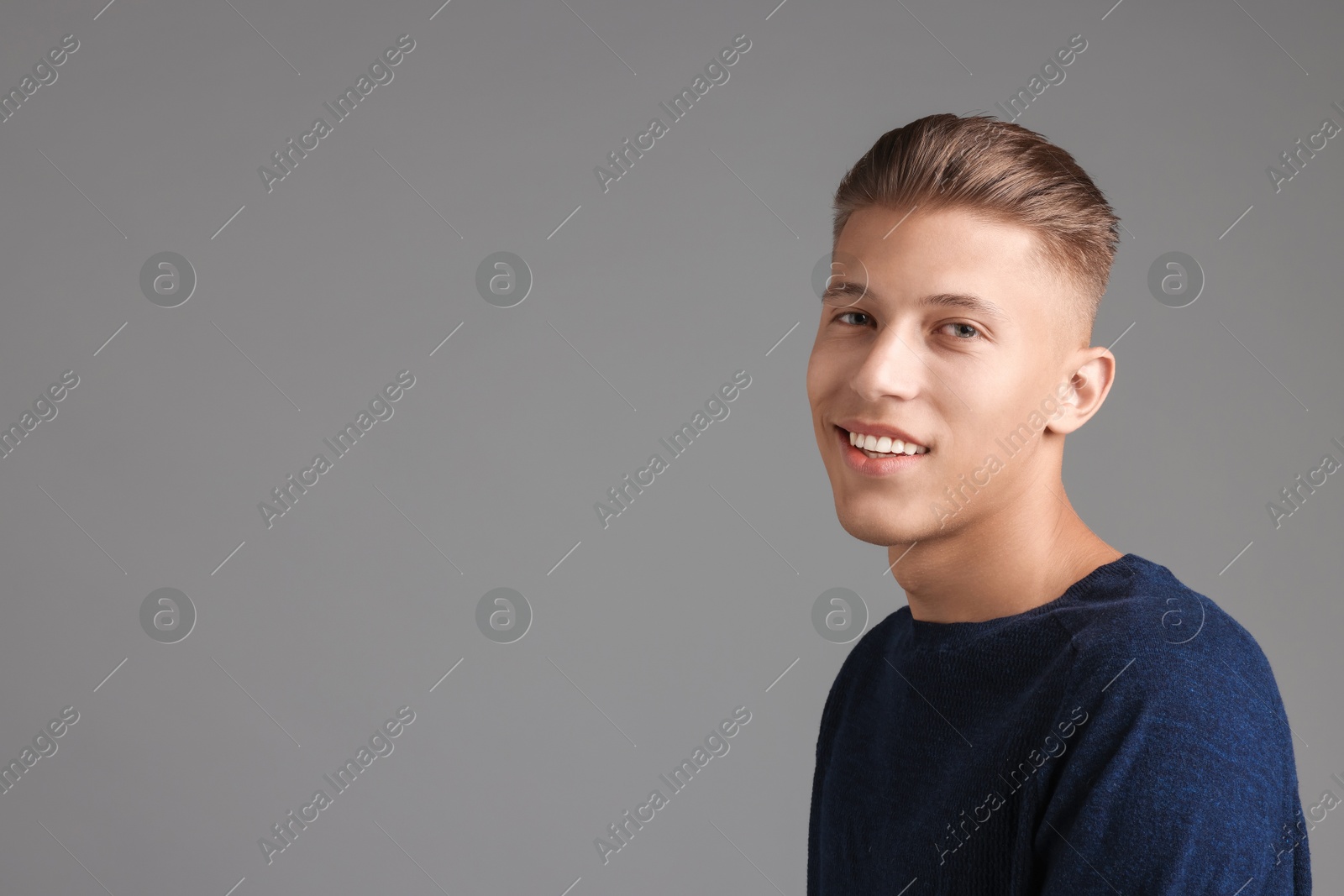 Photo of Handsome young man with stylish haircut on grey background. Space for text