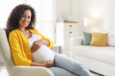 Photo of Portrait of beautiful pregnant woman in armchair at home