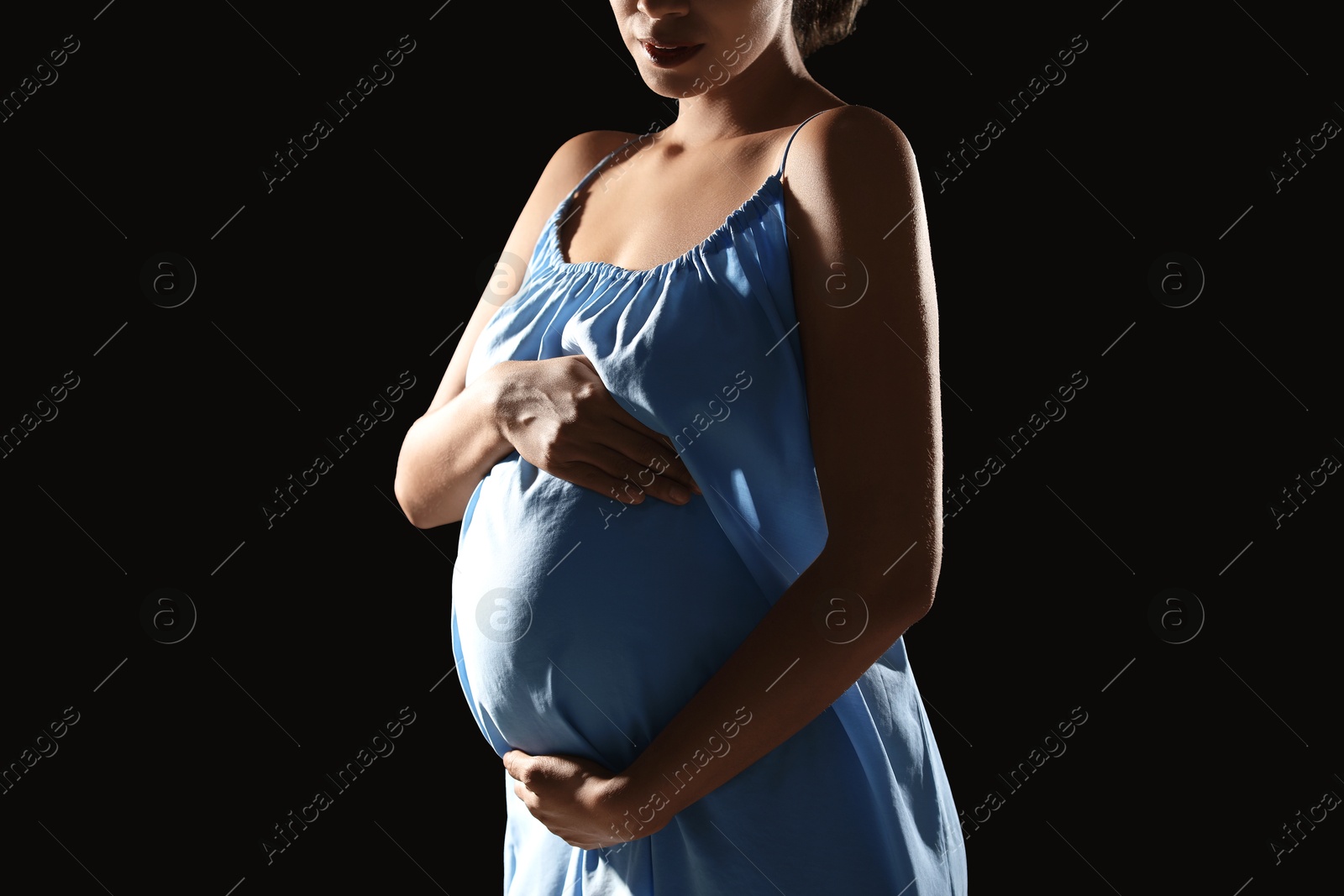 Photo of Pregnant woman on black background, closeup view