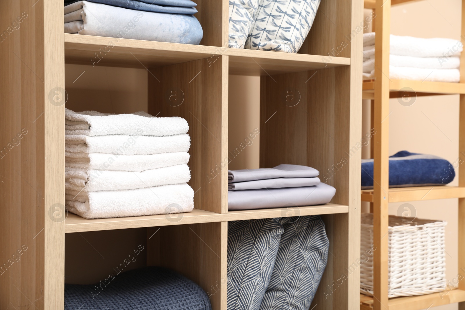 Photo of Different home textile on shelving units indoors, closeup