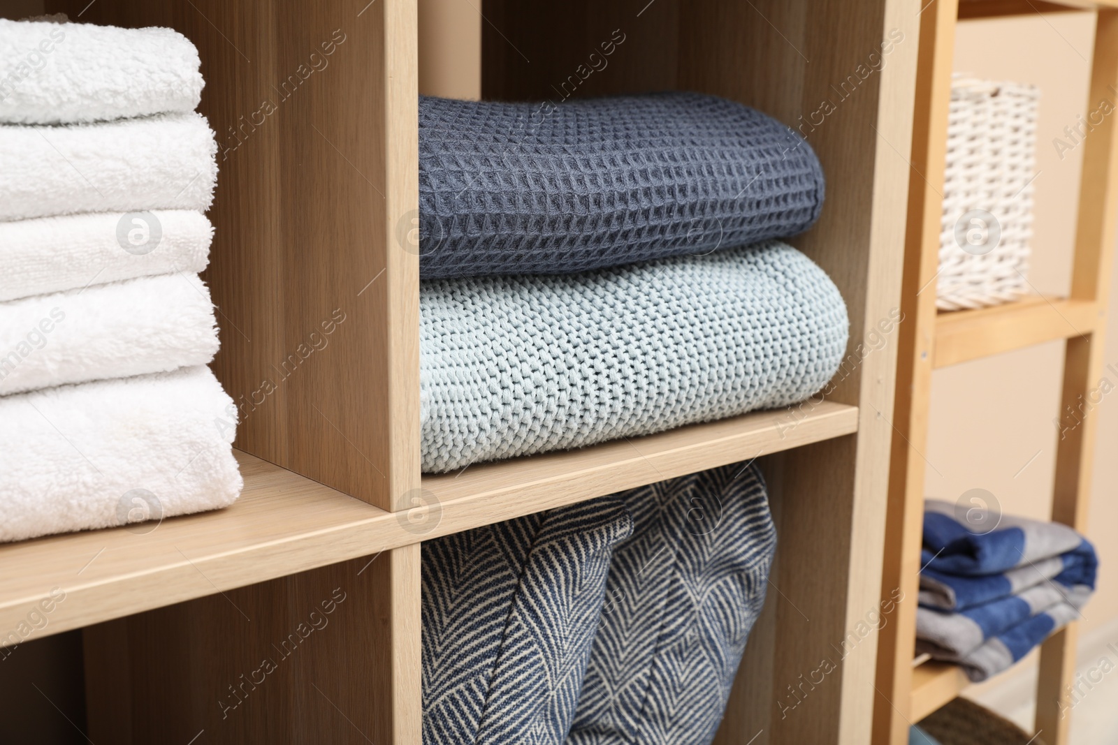 Photo of Different home textile on shelving units indoors, closeup