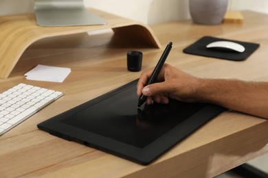 Photo of Professional retoucher working on graphic tablet at desk, closeup