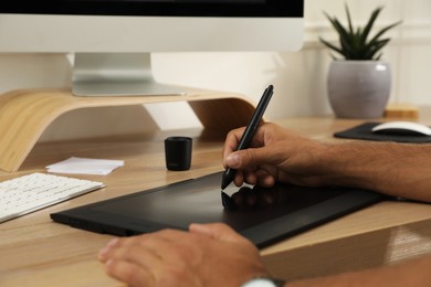 Professional retoucher working on graphic tablet at desk, closeup