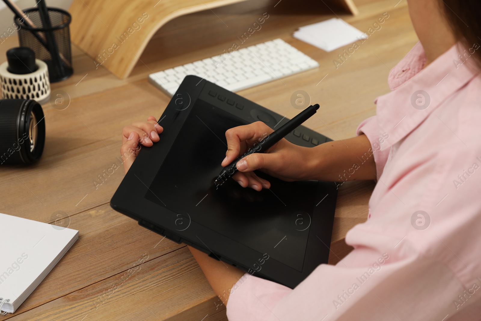 Photo of Professional retoucher working on graphic tablet at desk, closeup