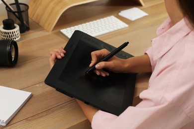 Photo of Professional retoucher working on graphic tablet at desk, closeup