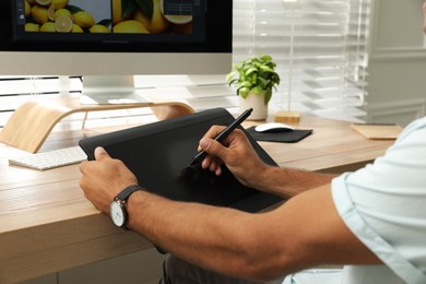 Photo of Professional retoucher working on graphic tablet at desk, closeup