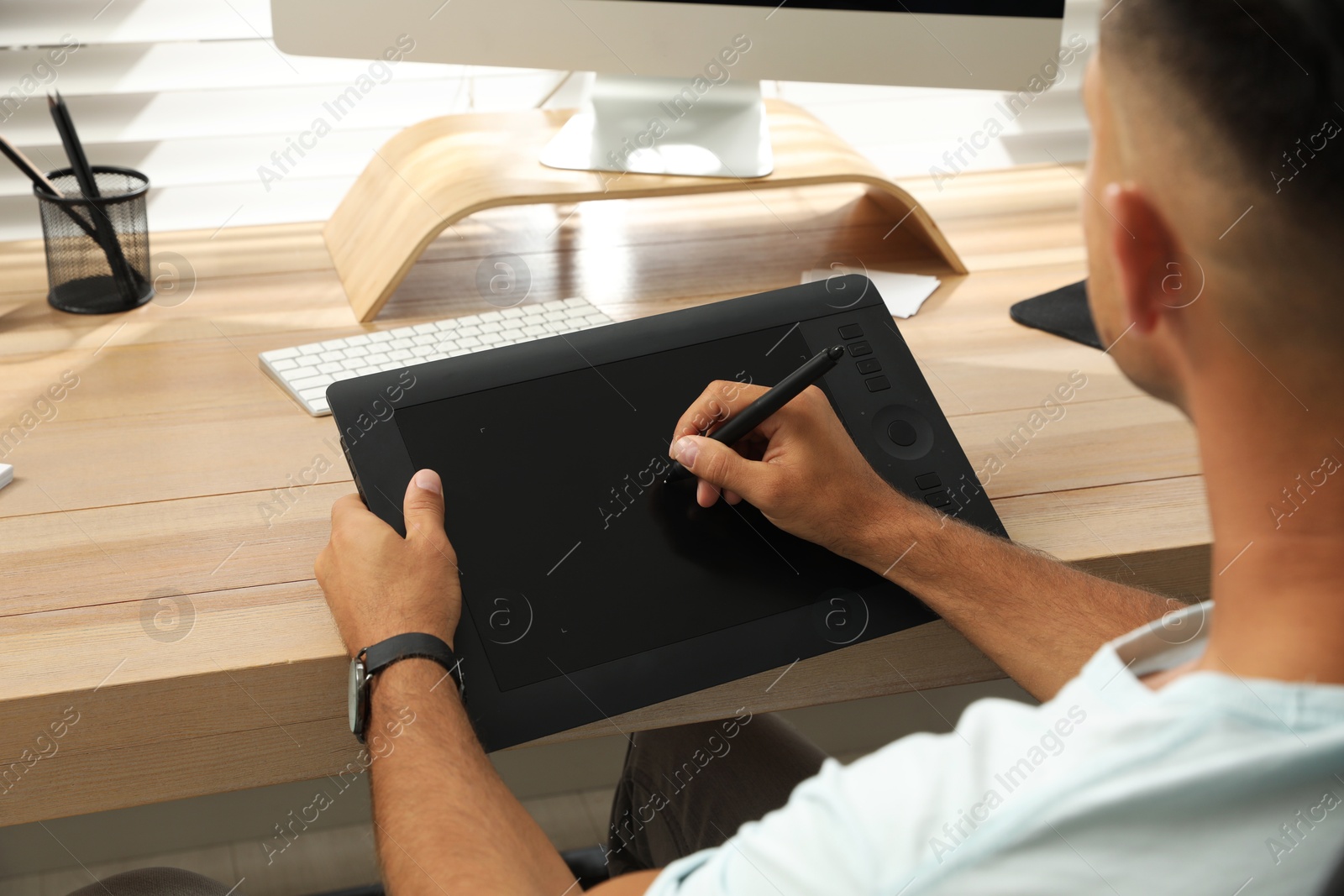 Photo of Professional retoucher working on graphic tablet at desk, closeup