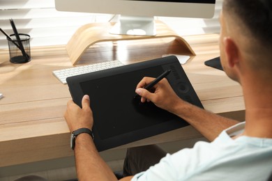 Professional retoucher working on graphic tablet at desk, closeup