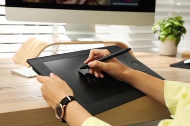 Photo of Professional retoucher working on graphic tablet at desk, closeup