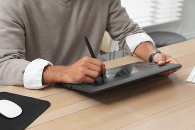 Professional retoucher working on graphic tablet at desk, closeup