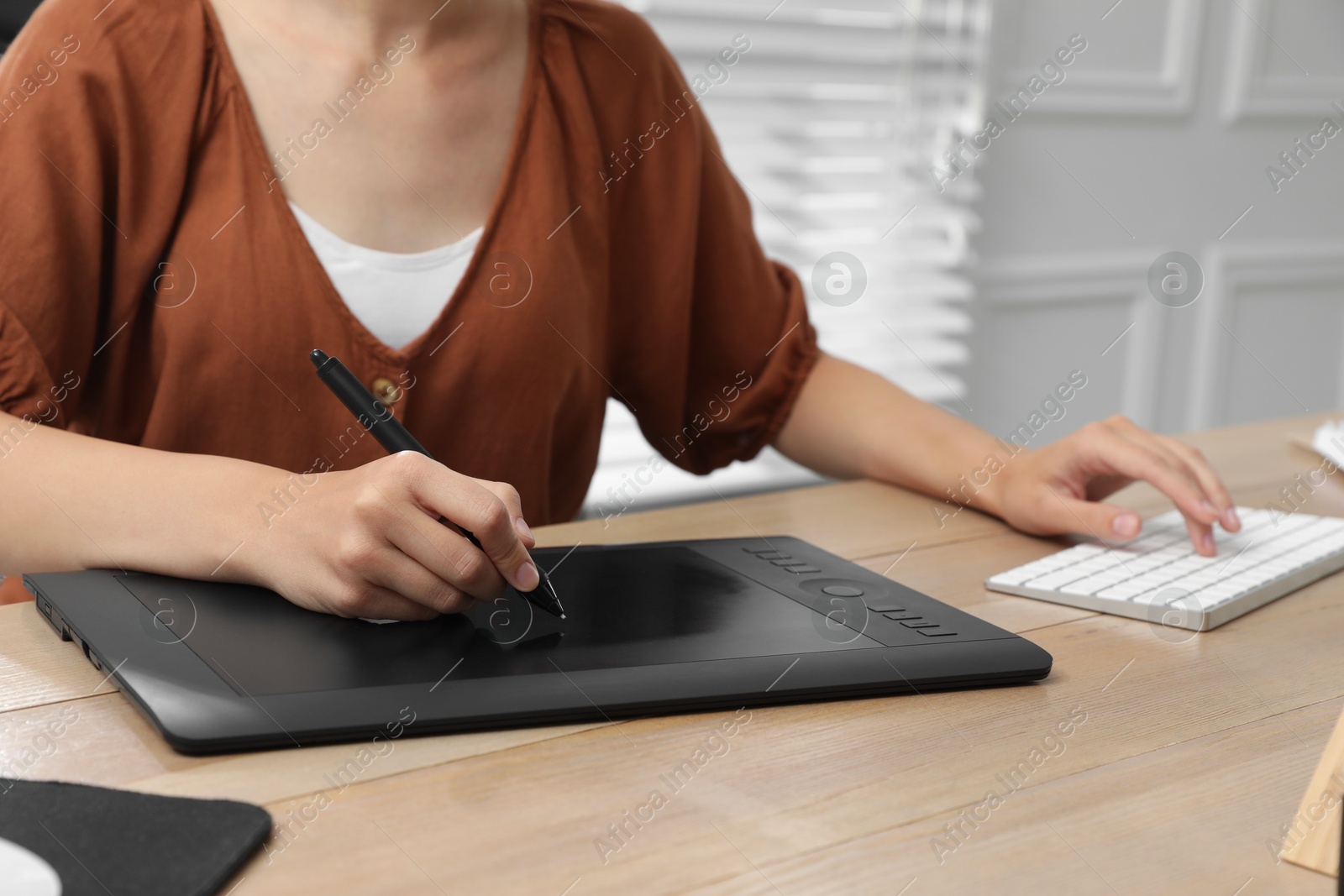 Photo of Professional retoucher working on graphic tablet at desk, closeup