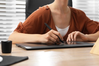 Professional retoucher working on graphic tablet at desk, closeup