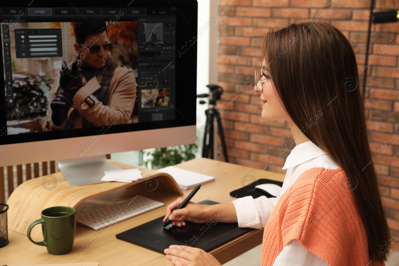 Photo of Professional retoucher working on graphic tablet at desk in office