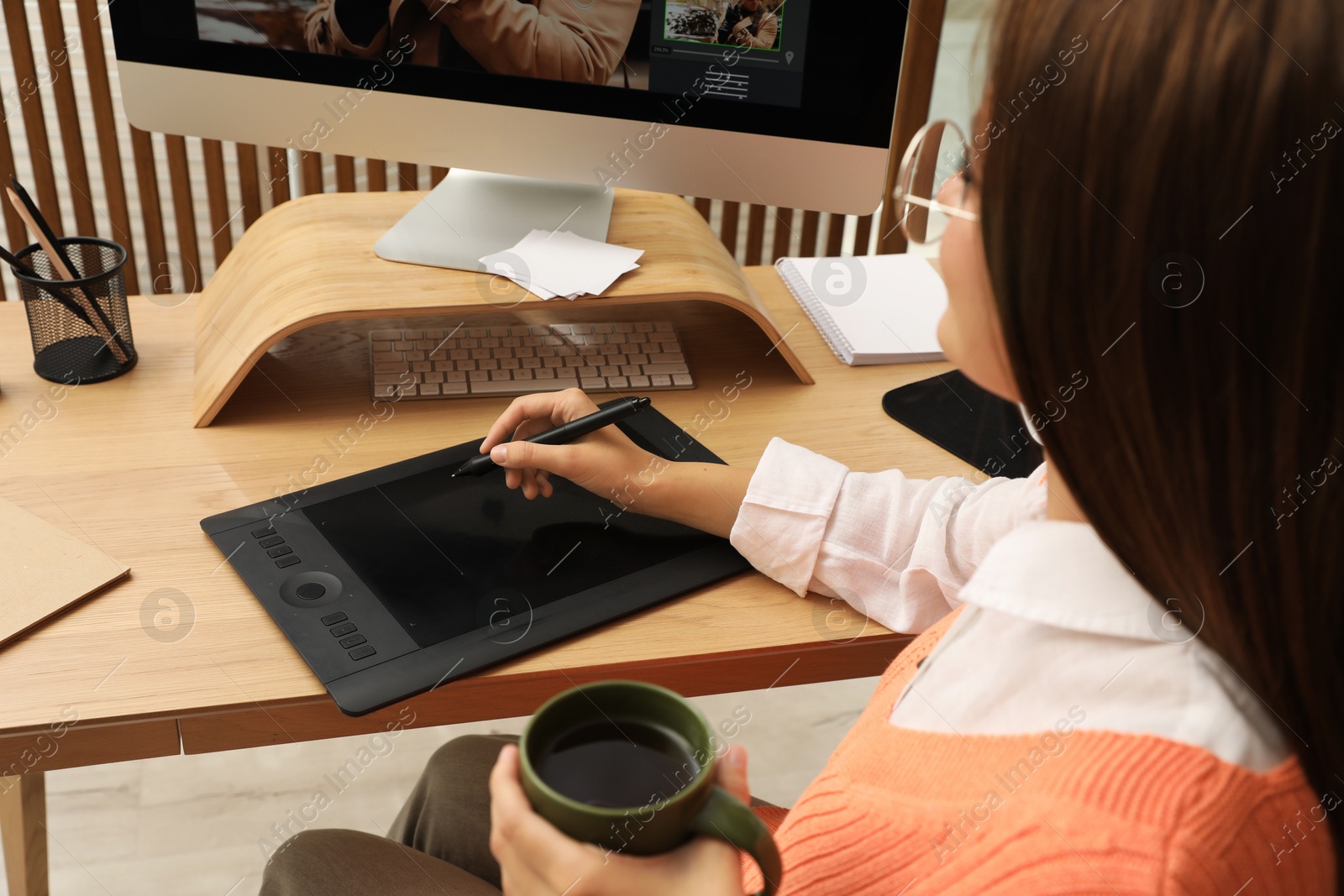 Photo of Professional retoucher working on graphic tablet at desk, closeup