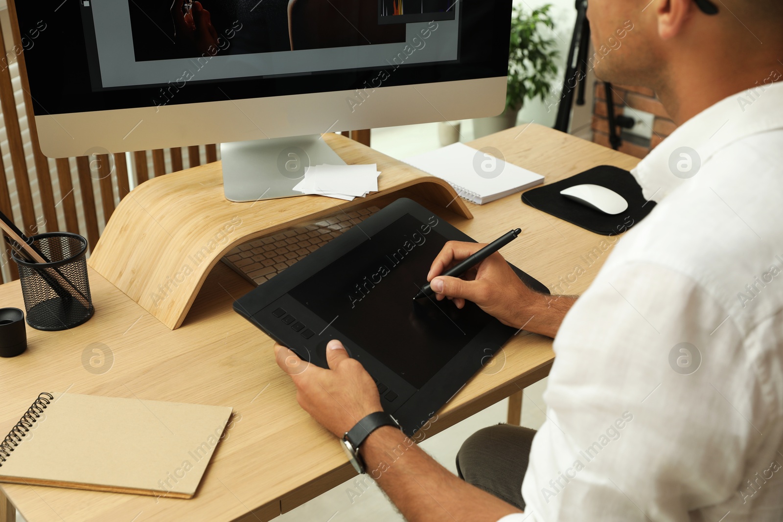 Photo of Professional retoucher working on graphic tablet at desk, closeup