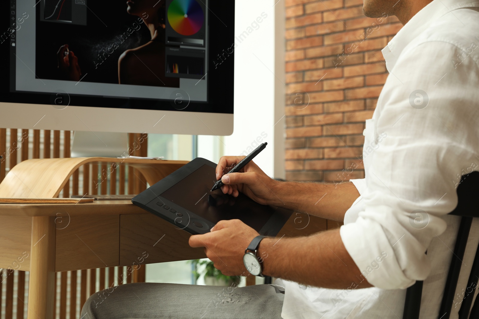 Photo of Professional retoucher working on graphic tablet at desk, closeup