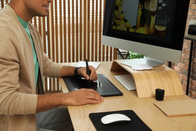 Photo of Professional retoucher working on graphic tablet at desk, closeup