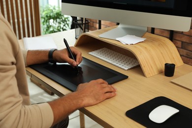 Photo of Professional retoucher working on graphic tablet at desk, closeup