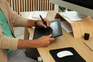 Photo of Professional retoucher working on graphic tablet at desk, closeup