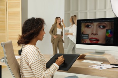 Photo of Professional African American retoucher working with graphic tablet at desk in photo studio