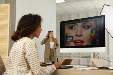 Professional African American retoucher working with graphic tablet at desk in photo studio