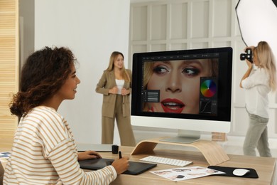 Photo of Professional African American retoucher working with graphic tablet at desk in photo studio