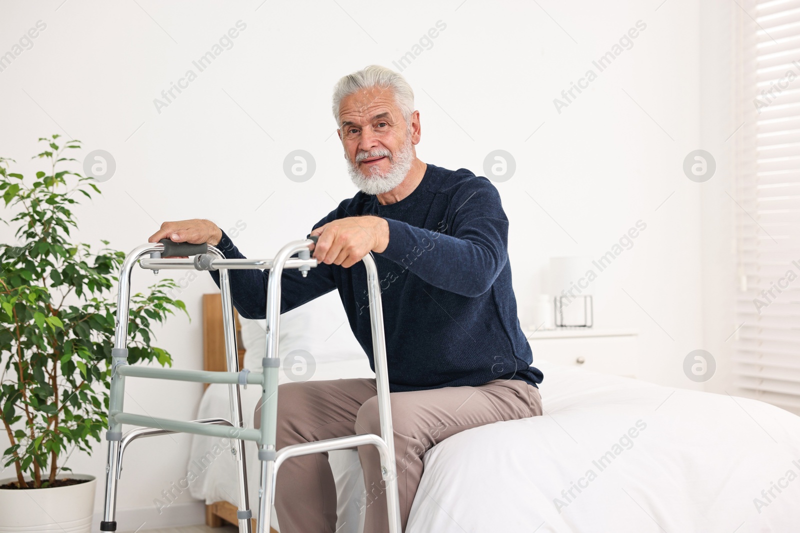 Photo of Senior man with walking frame on bed in hospital ward