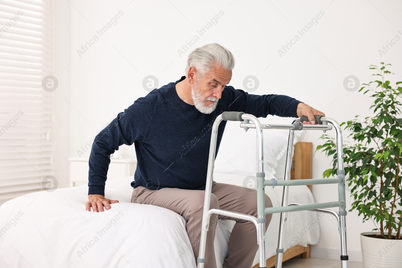 Photo of Senior man with walking frame on bed in hospital ward