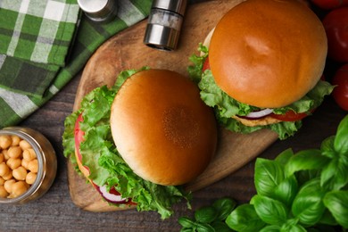 Delicious vegetarian burgers with chickpea cutlets on wooden table, flat lay