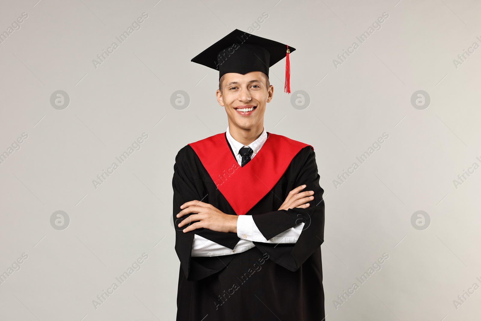 Photo of Happy student with crossed arms after graduation on grey background