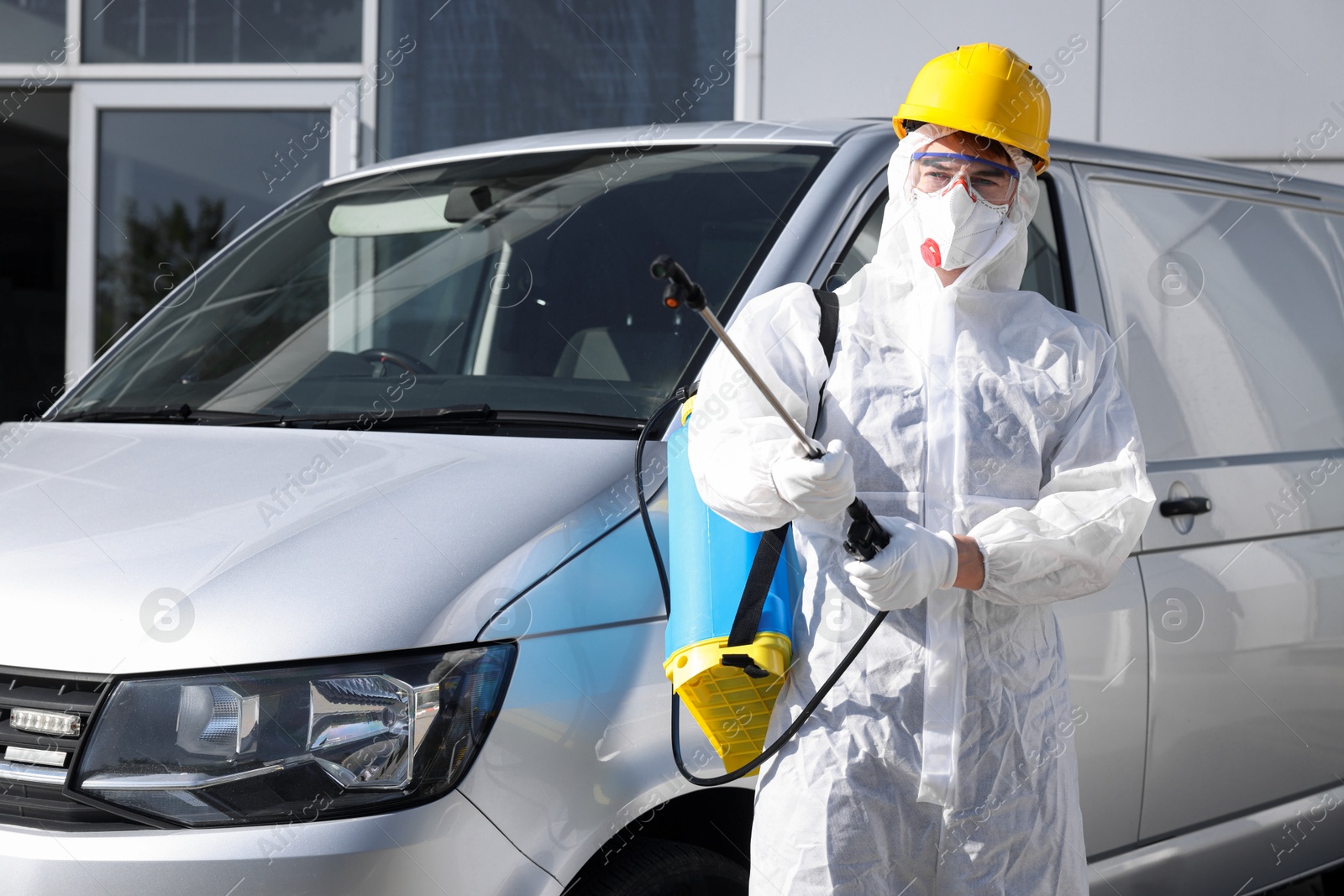 Photo of Pest control worker with spray tank near gray minibus outdoors