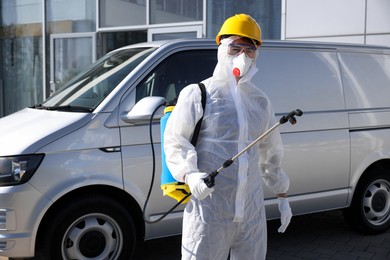 Pest control worker with spray tank outdoors