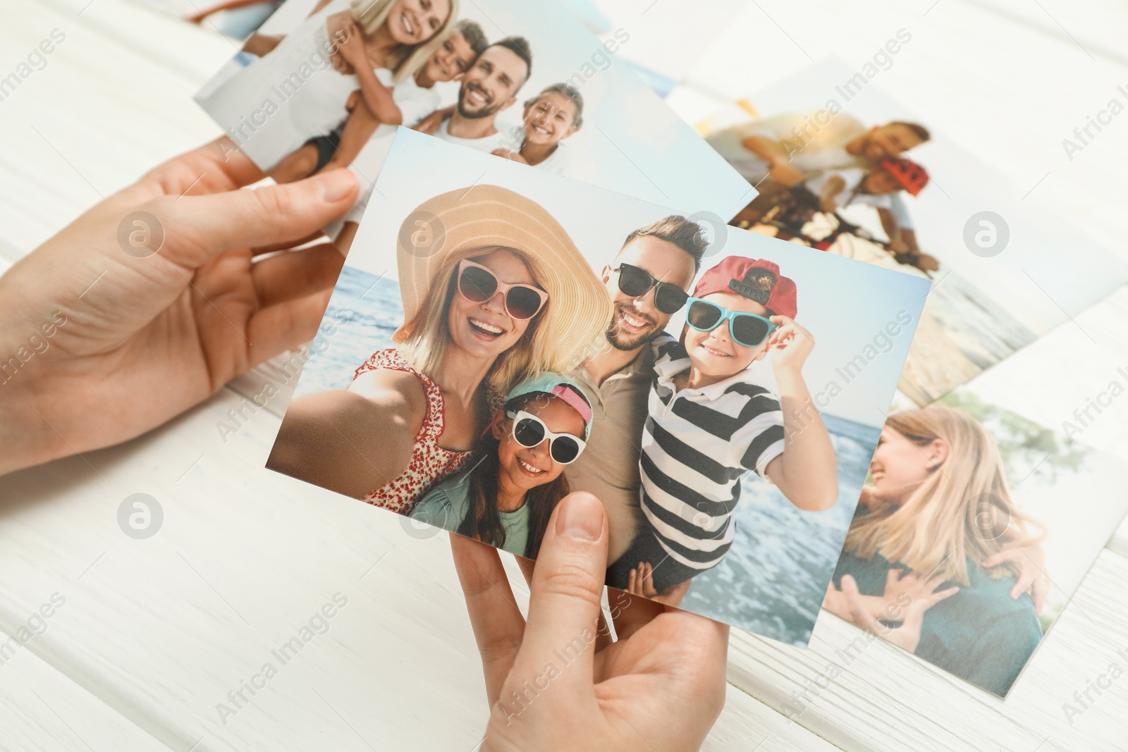 Photo of Woman with different photos at white wooden table, closeup