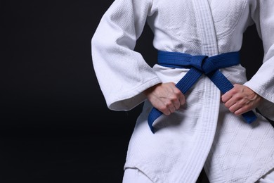 Photo of Karate fighter in kimono on black background, closeup. Space for text