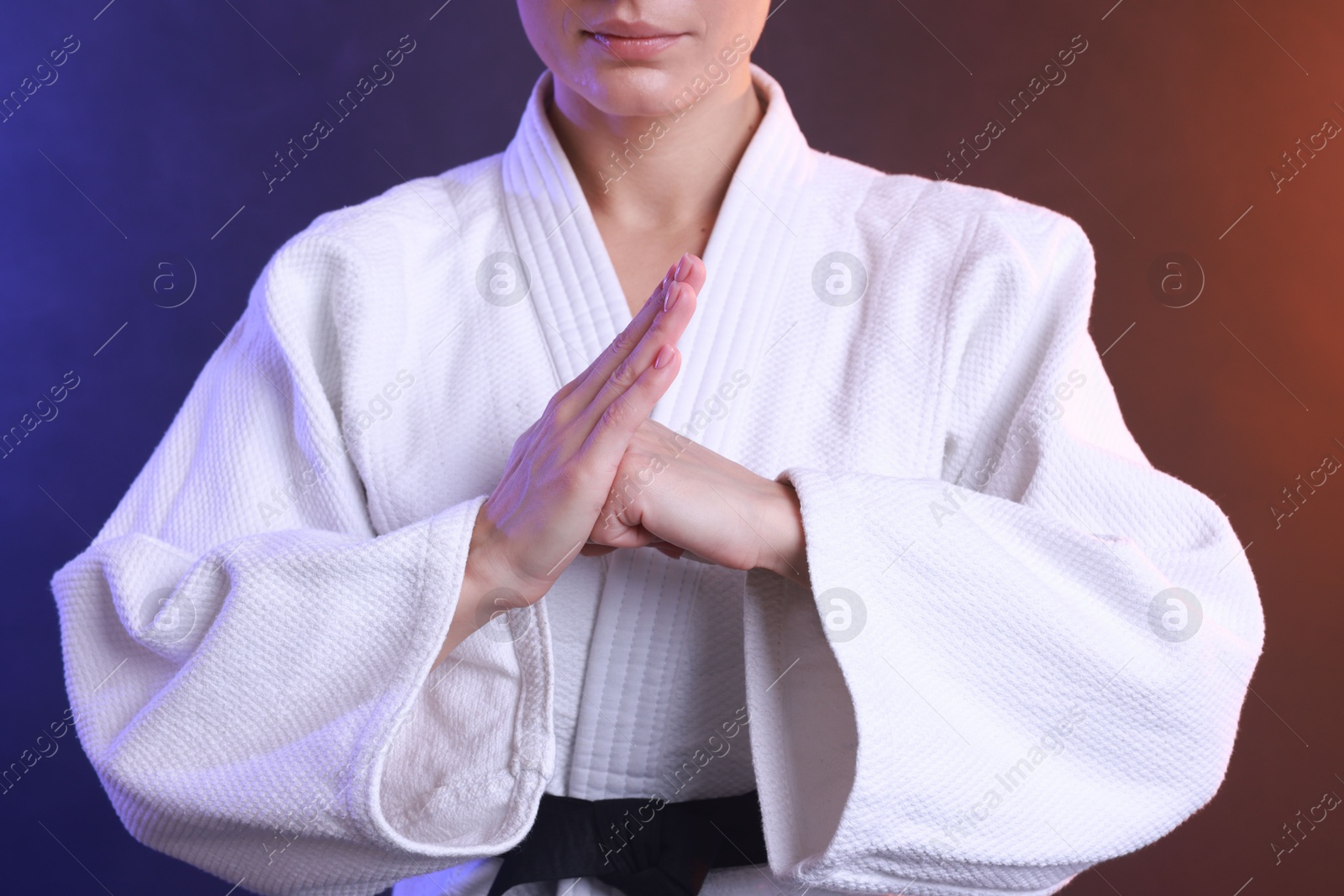 Photo of Karate fighter in kimono on color background, closeup