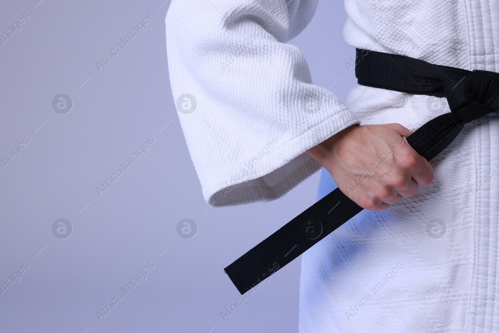 Photo of Karate fighter in kimono on light background, closeup. Space for text