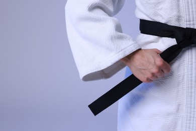 Photo of Karate fighter in kimono on light background, closeup. Space for text