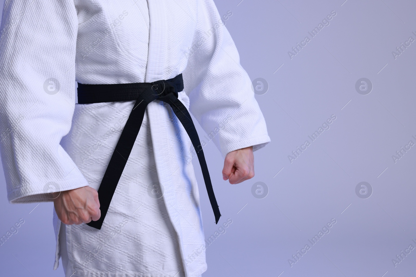 Photo of Karate fighter in kimono on light background, closeup. Space for text