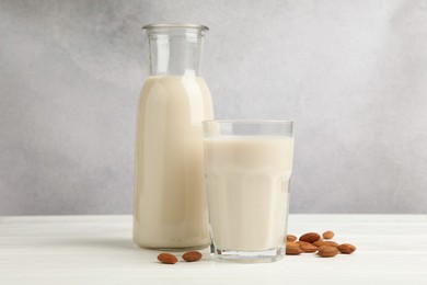 Photo of Fresh nut milk and almonds on white wooden table