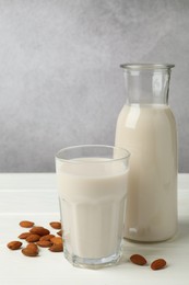 Photo of Fresh nut milk and almonds on white wooden table