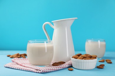 Fresh nut milk and almonds on light blue wooden table