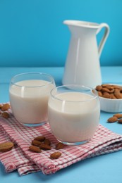 Photo of Fresh nut milk and almonds on light blue wooden table